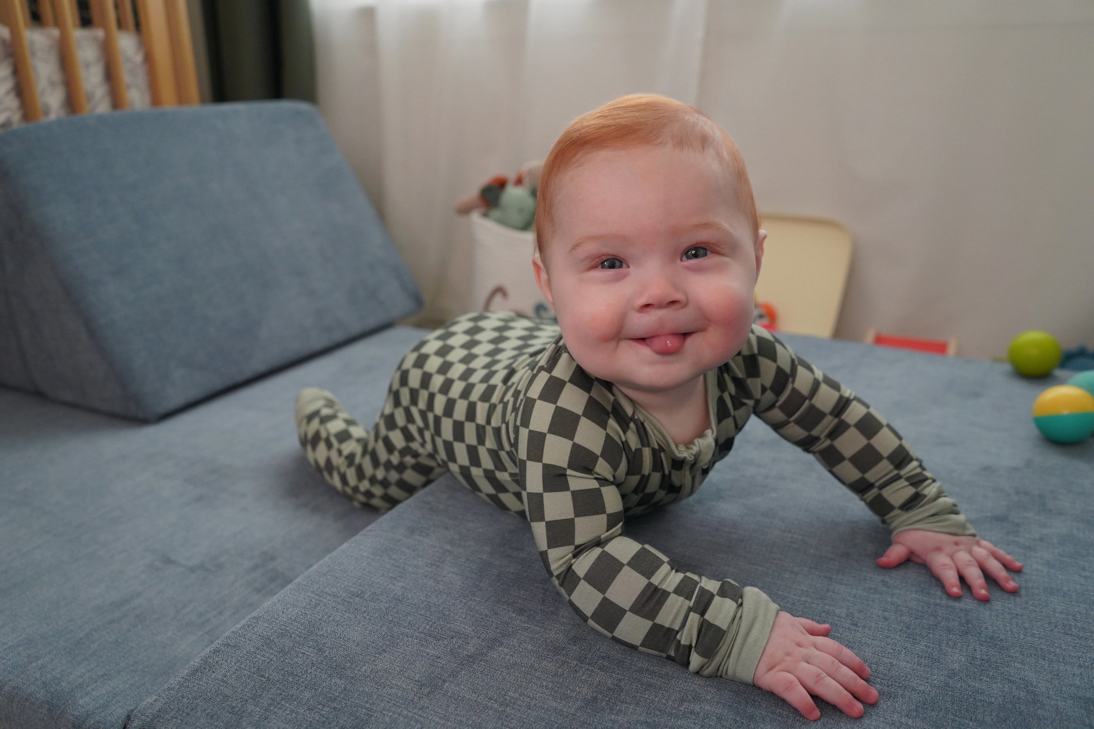 Baby in Evergreen Zippy on play couch.